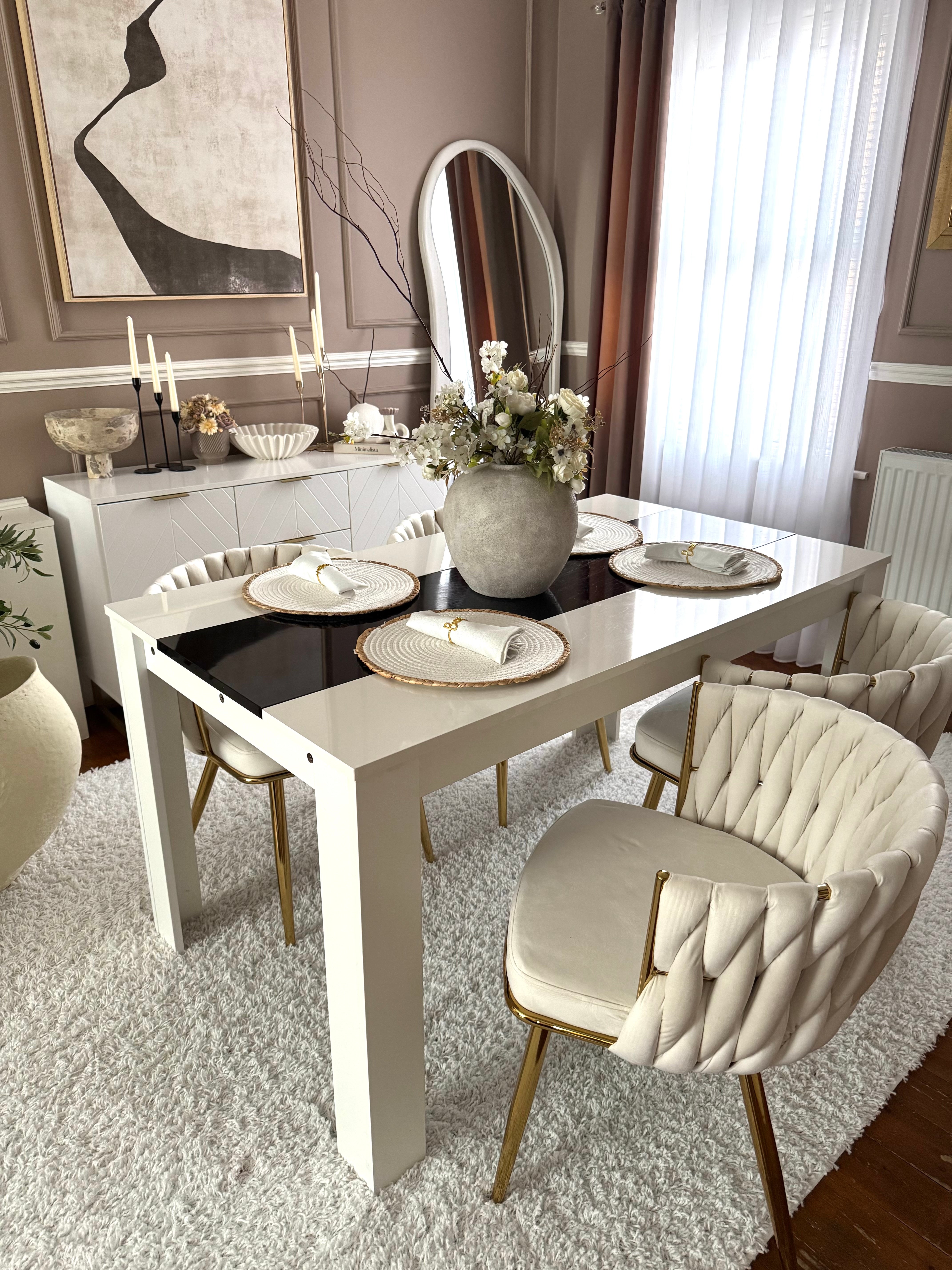 Dining room with a white table and chairs, featuring a vase of flowers and decorative items.